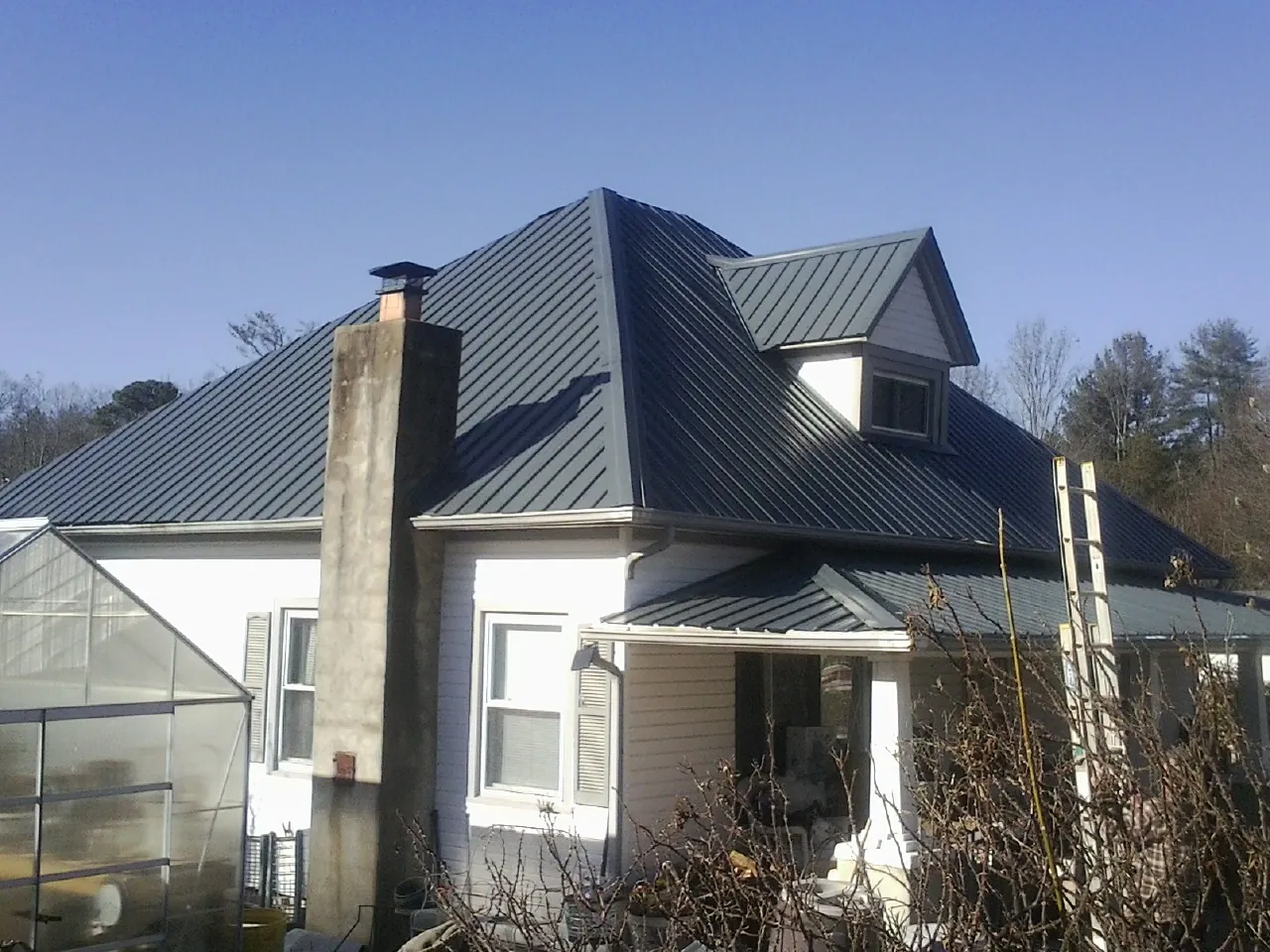 Dark blue standing seam metal roof on a white farmhouse with dormer — Slate & Tile Roof Repair by Roofing Brothers in Wallpack Center