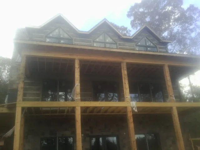 Dormers and porch framing on a large log home under construction — Roof Coating work by our crew in Wallpack Center