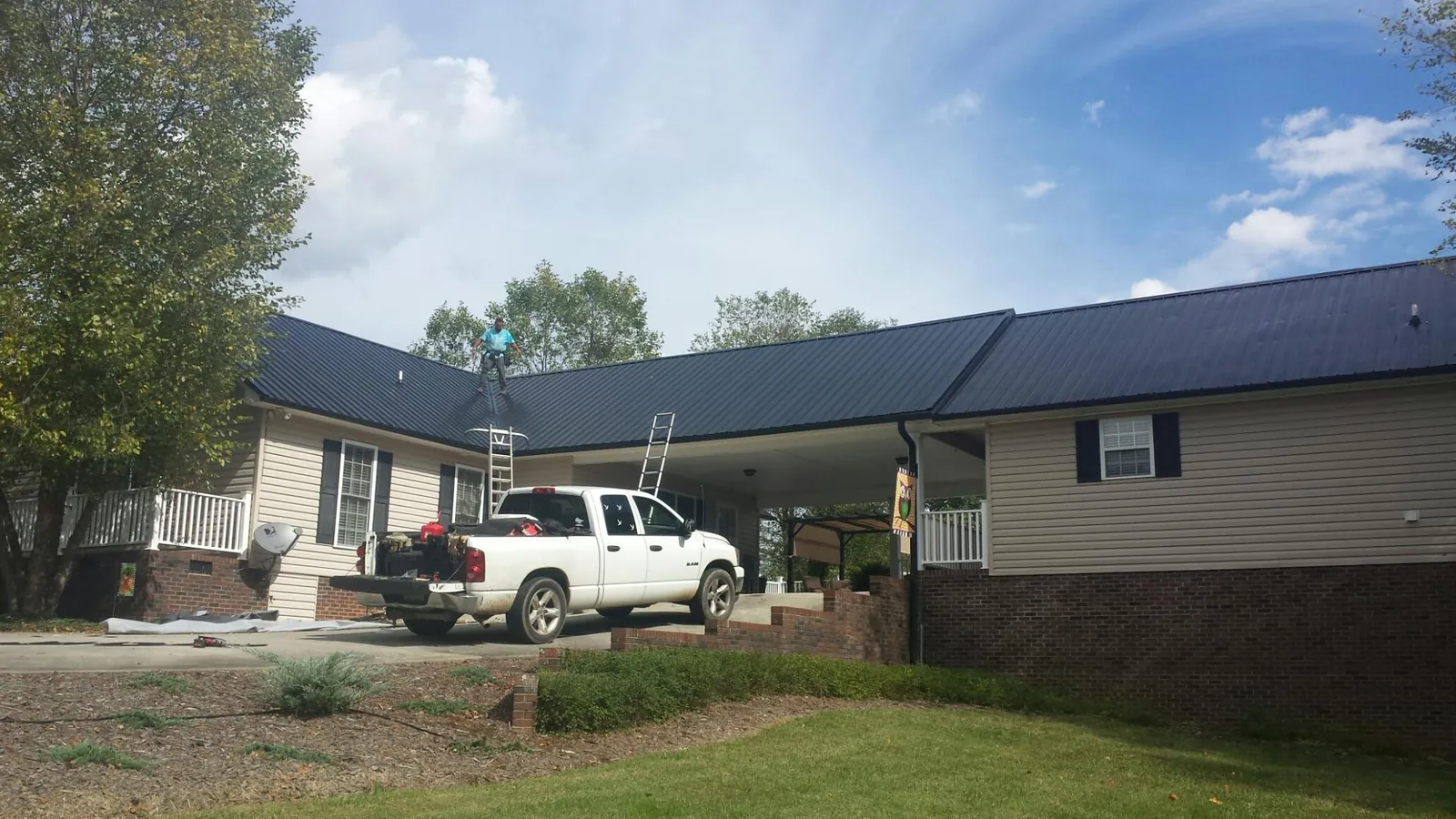 Black metal roof over a home and attached breezeway with ladders set in Wallpack Center