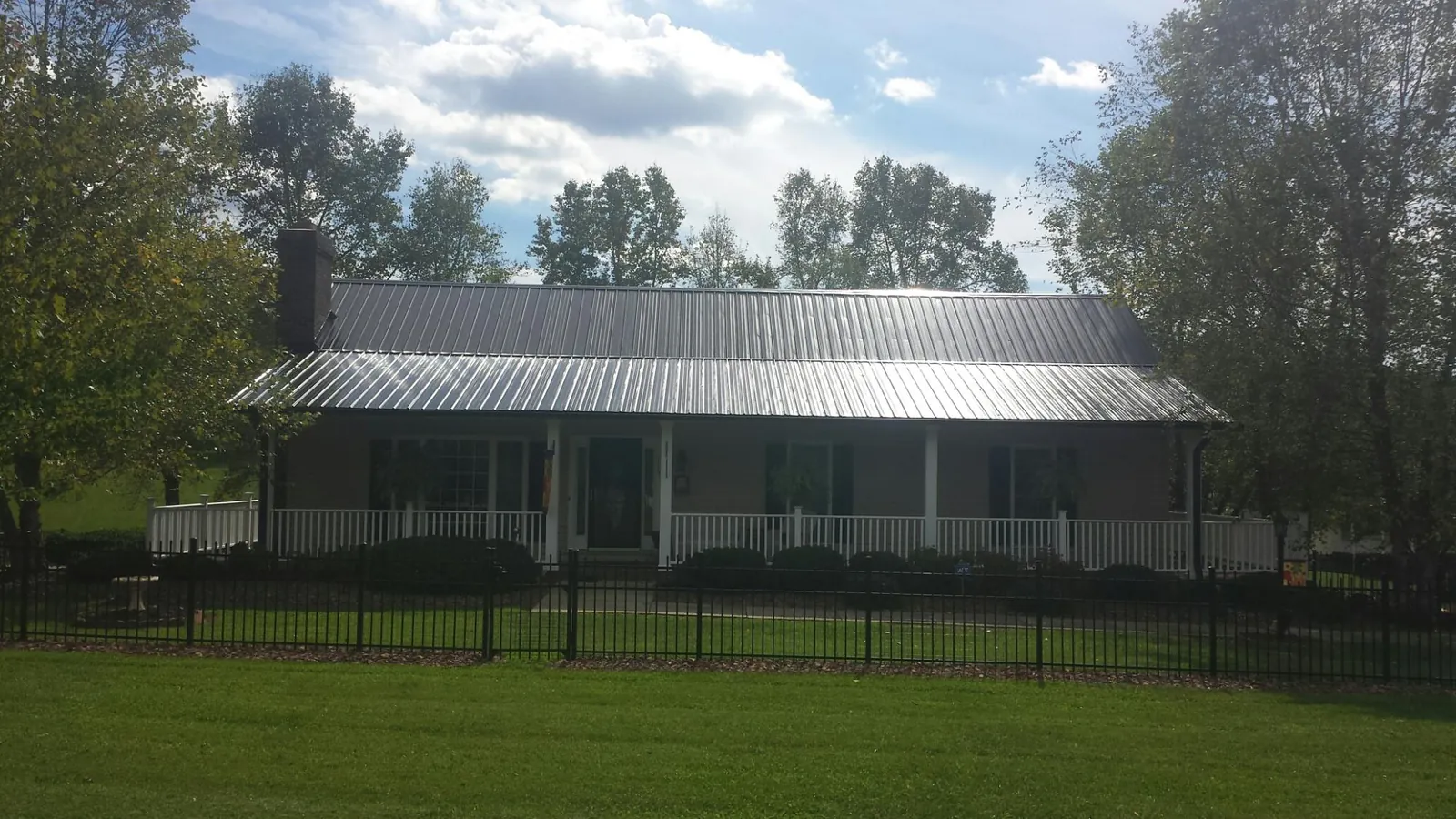 Gray metal roof on a brick ranch with a full width front porch — Gutter Guard Installation work by our crew in Wallpack Center
