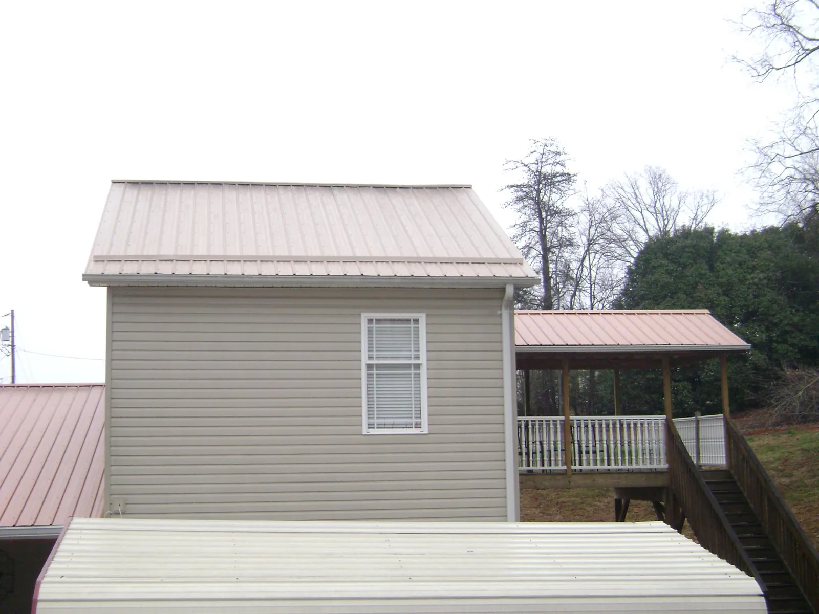 Tan metal roofs on a two story addition and attached porch, from a Roof Replacement job in Wallpack Center