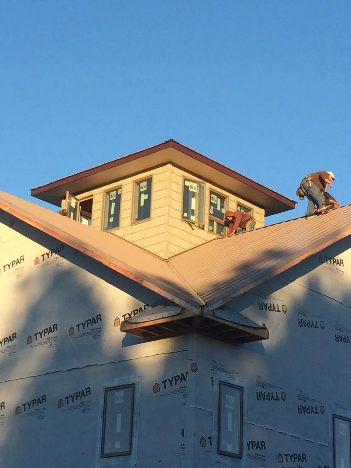 Roofers working around a rooftop cupola on a new metal roof at sunset — Roof Waterproofing in Wallpack Center by Roofing Brothers